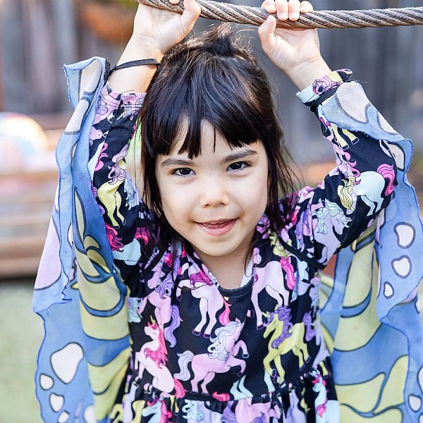 A kinder girl wearing butterfly wings holds onto a rope swing at her kindergarten in Melbourne Australia.jpg