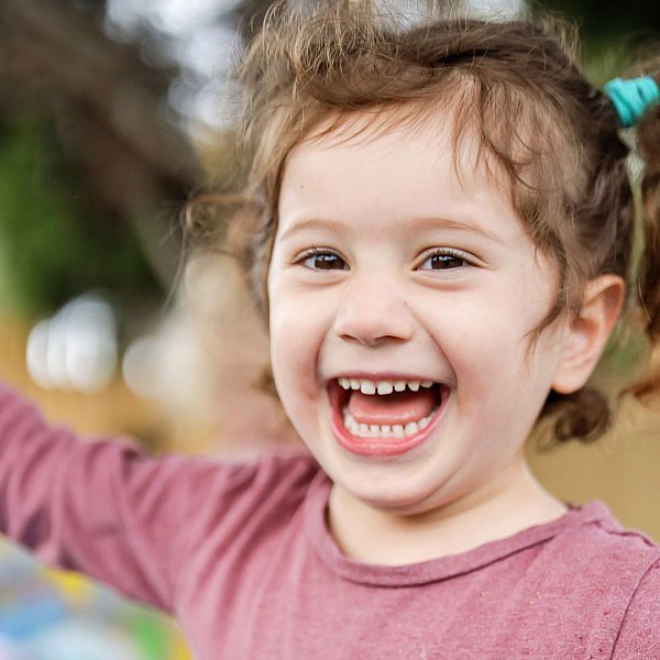 image shows a small girl laughing at her childcare centre.jpg