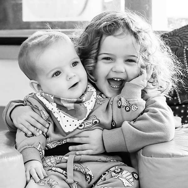 image shows a big sister cuddling her little baby brother at childcare.jpg