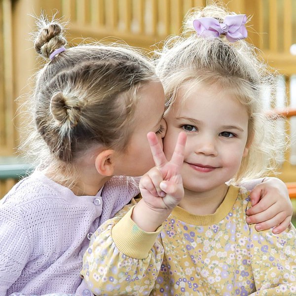 image shows two girl cousins sharing a hug at daycare.jpg