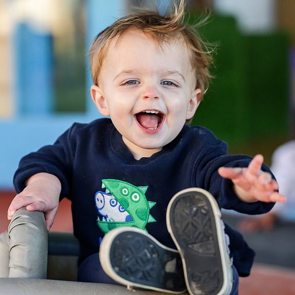 image shows a young toddler kicking up his heels at daycare.jpg